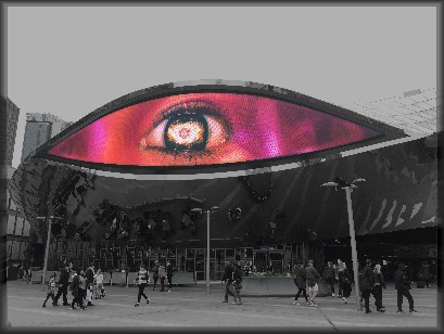 Photo of an eye on an electronic billboard. The rest of the image is desaturated.
